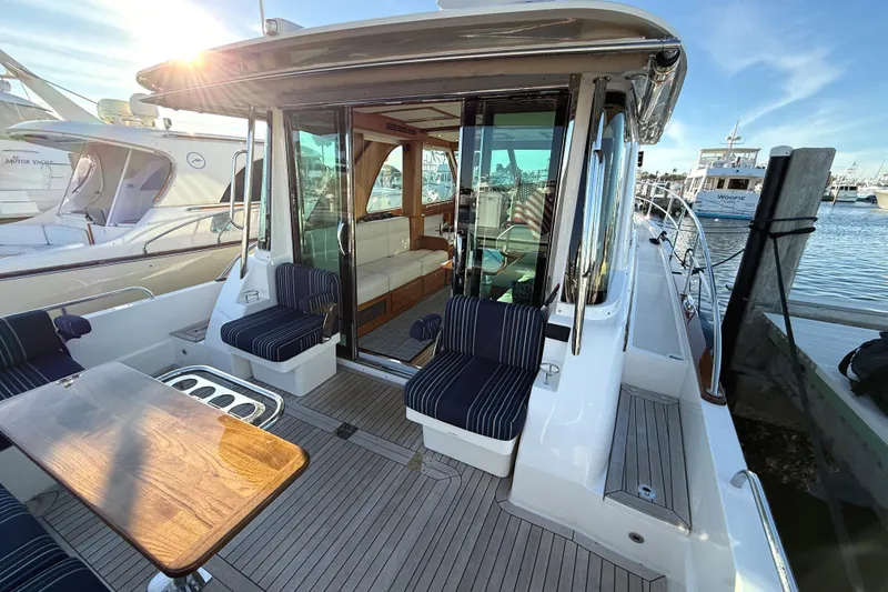 Slide: The Image of 2023 Sabre 43 Salon Express yacht with elegant seating and wooden deck at a marina. - 11