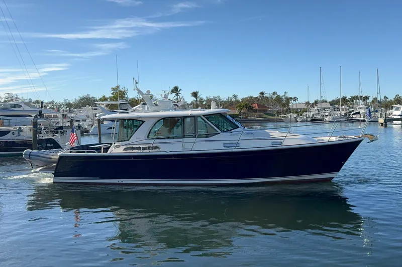 Slide: The Image of 2023 Sabre 43 Salon Express yacht on calm water, docked at a marina. - 3