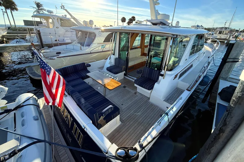 Slide: The Image of 2023 Sabre 43 Salon Express yacht docked, featuring spacious seating and American flag. - 7