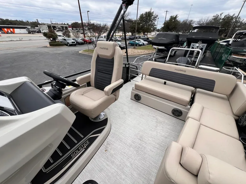 Slide: The Image of 2025 Harris Solstice 230 boat interior with beige seating and steering console. - 23