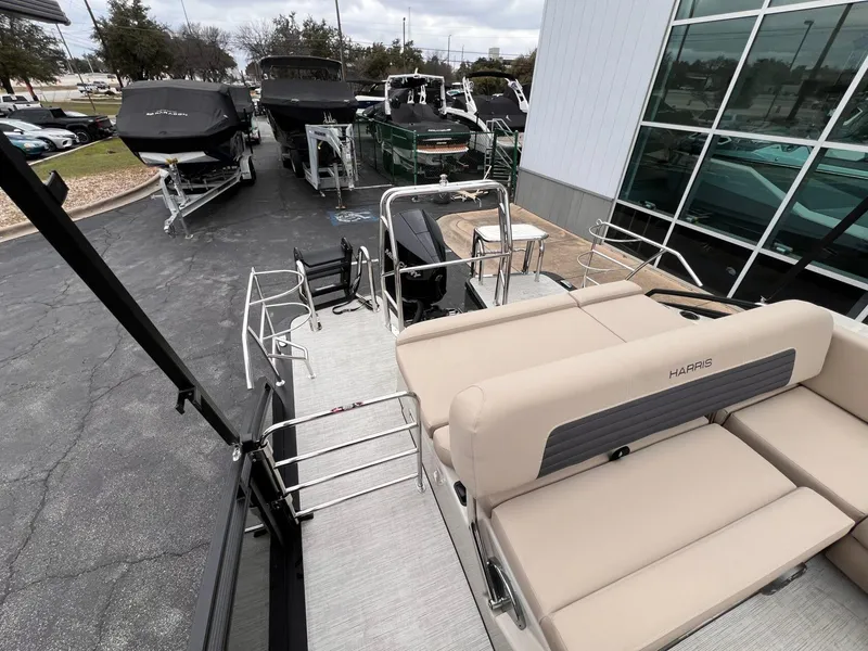 Slide: The Image of 2025 Harris Solstice 230 pontoon boat with beige seating, parked near other boats. - 26