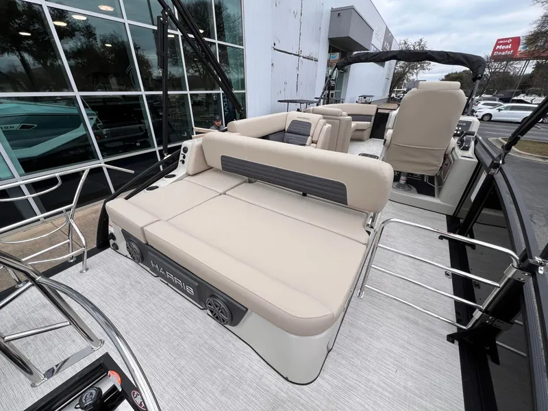 Slide: The Image of 2025 Harris Solstice 230 pontoon boat with beige seating, docked near a modern building. - 29