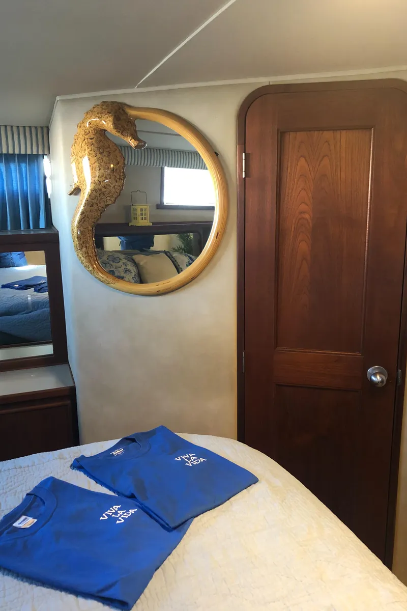 Slide: The Image of 1987 Chris-Craft 426 Catalina cabin interior with seahorse decor and blue shirts on bed. - 18