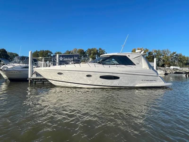 The Image of 2015 Regal 42 Sport Coupe yacht docked on calm water under clear blue sky. - 0