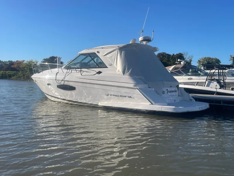 Slide: The Image of 2015 Regal 42 Sport Coupe yacht docked on calm water under clear blue sky. - 2