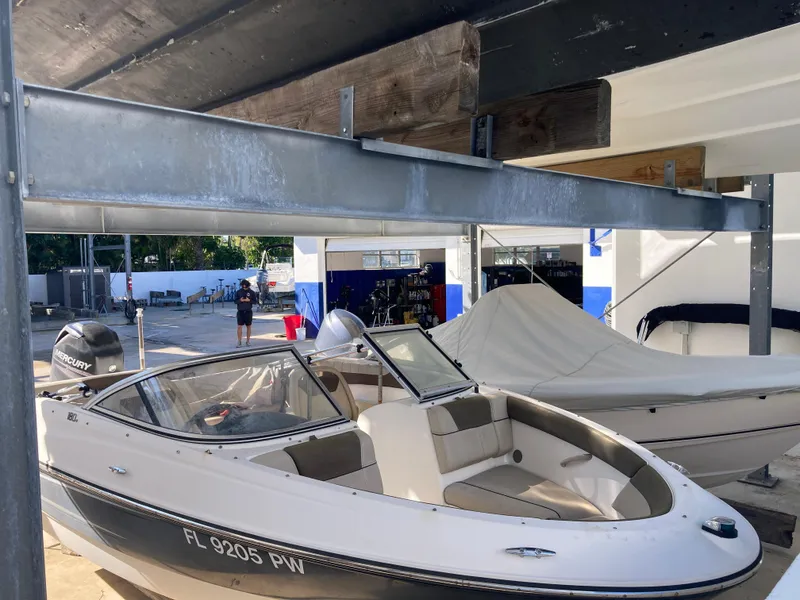 Slide: The Image of 2014 Bayliner 180 Bowrider boat in storage facility, partially covered. - 1