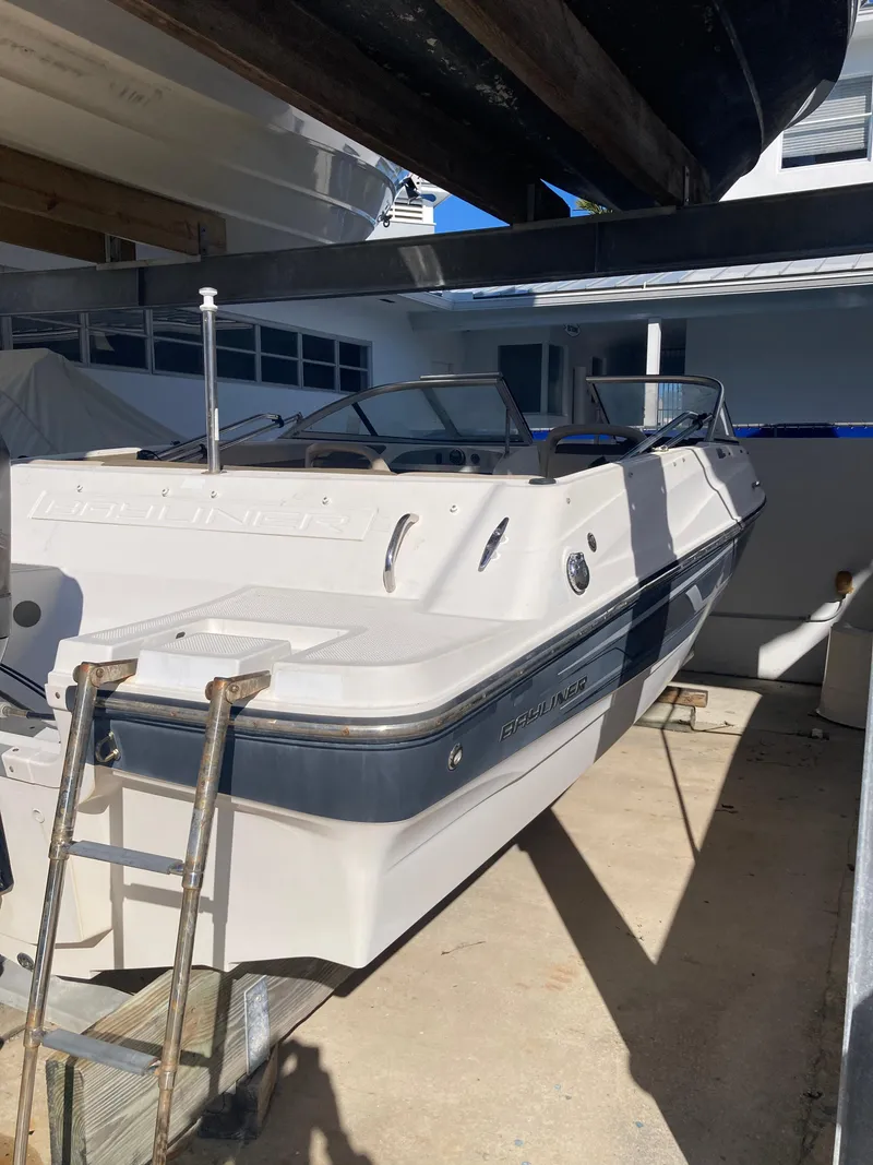 Slide: The Image of 2014 Bayliner 180 Bowrider boat in storage, featuring sleek design and spacious seating. - 13