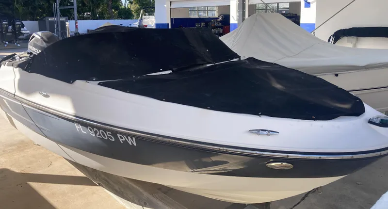 Slide: The Image of 2014 Bayliner 180 Bowrider boat with cover, parked in a marina. - 2
