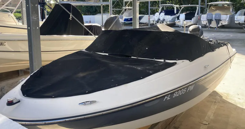 Slide: The Image of 2014 Bayliner 180 Bowrider boat with black cover in a marina. - 3