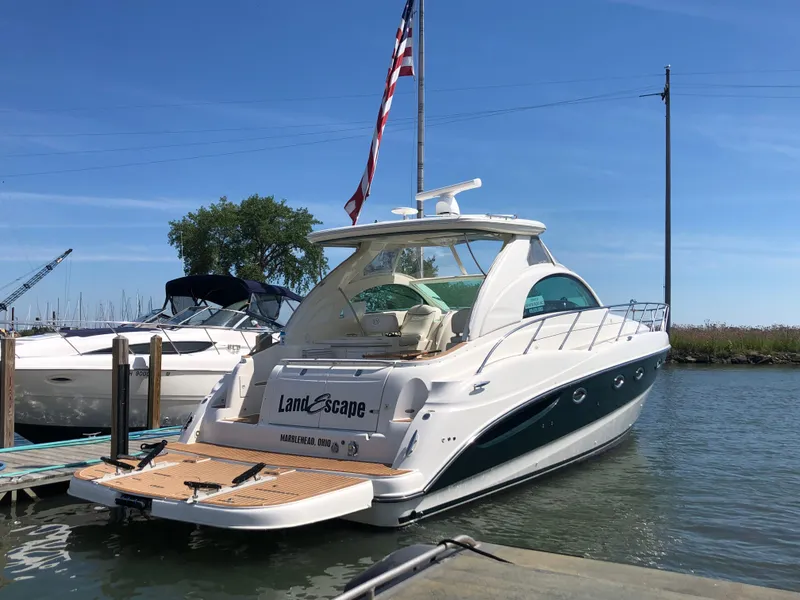 Slide: The Image of 2002 Maxum 4200 SCR yacht docked with American flag, clear sky background. - 8