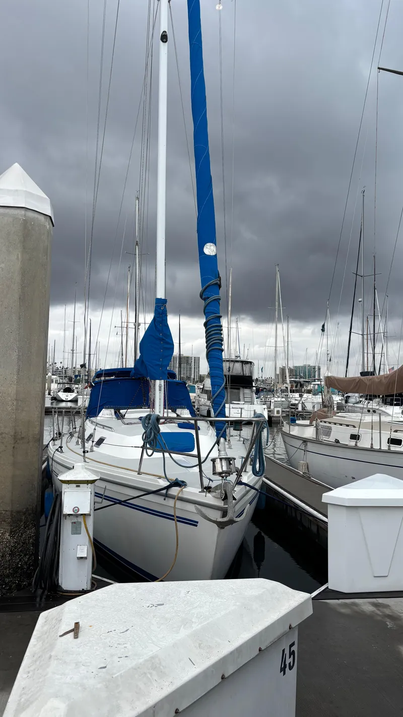 Slide: The Image of 1994 Catalina 36 sailboat docked under cloudy skies at a marina. - 10