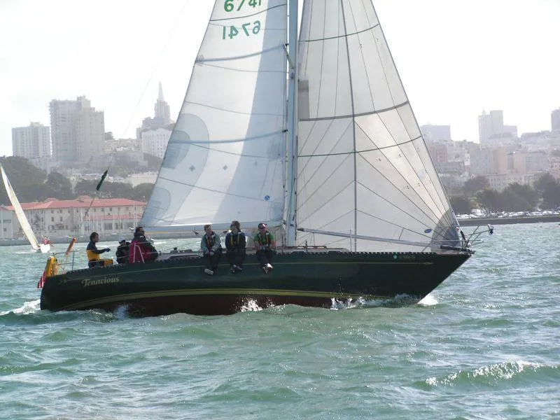 Slide: The Image of 1978 Islander sailboat navigating urban waters with crew onboard. - 0