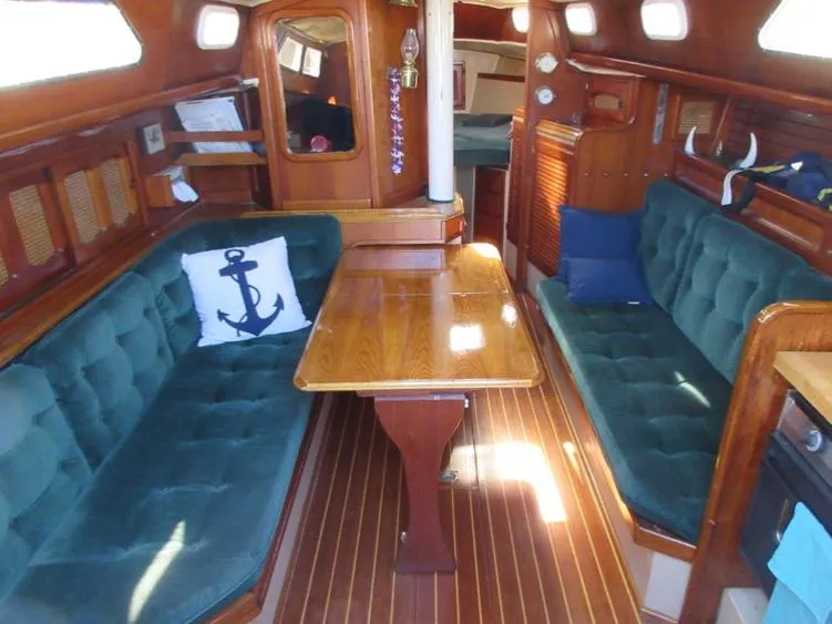 Slide: The Image of 1978 Islander sailboat interior with wooden table, green cushioned seating, and nautical decor. - 1