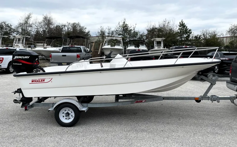 Slide: The Image of 2003 Boston Whaler 150 Sport boat on trailer in parking lot. - 2
