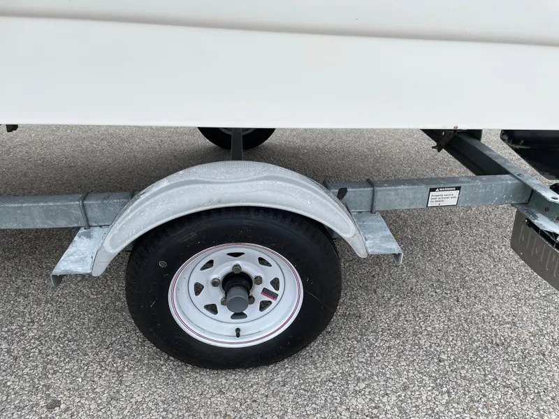 Slide: The Image of Trailer wheel of a 2003 Boston Whaler 150 Sport boat on pavement. - 22