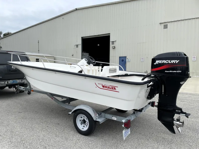 Slide: The Image of 2003 Boston Whaler 150 Sport boat with Mercury engine on trailer, parked outside a warehouse. - 6