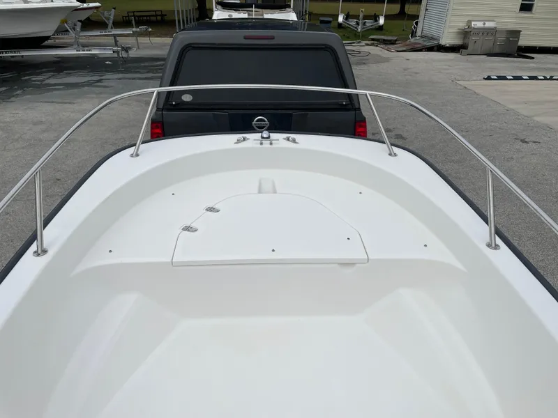 Slide: The Image of 2003 Boston Whaler 150 Sport boat bow view, parked near a vehicle. - 9