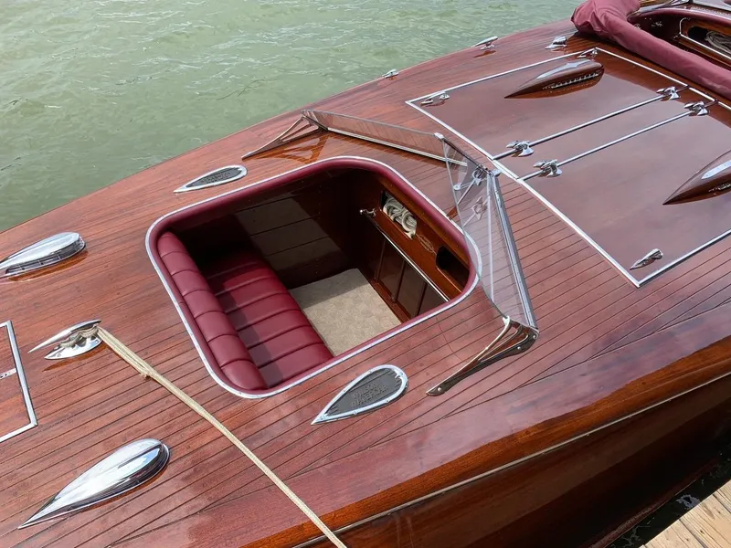 Slide: The Image of Classic 2021 Wilson Watercar with polished wood finish and red leather interior on water. - 11