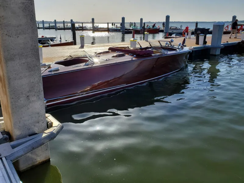 Slide: The Image of 2021 Classic Wilson Watercar docked at a marina, reflecting sunlight on calm water. - 2