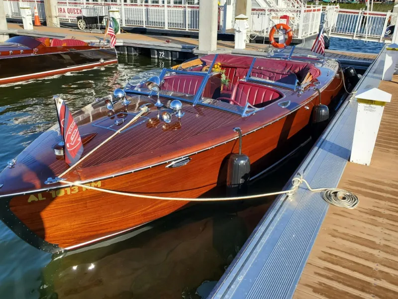 Slide: The Image of Classic 2021 Wilson Watercar docked, featuring polished wood finish and maroon interior. - 5
