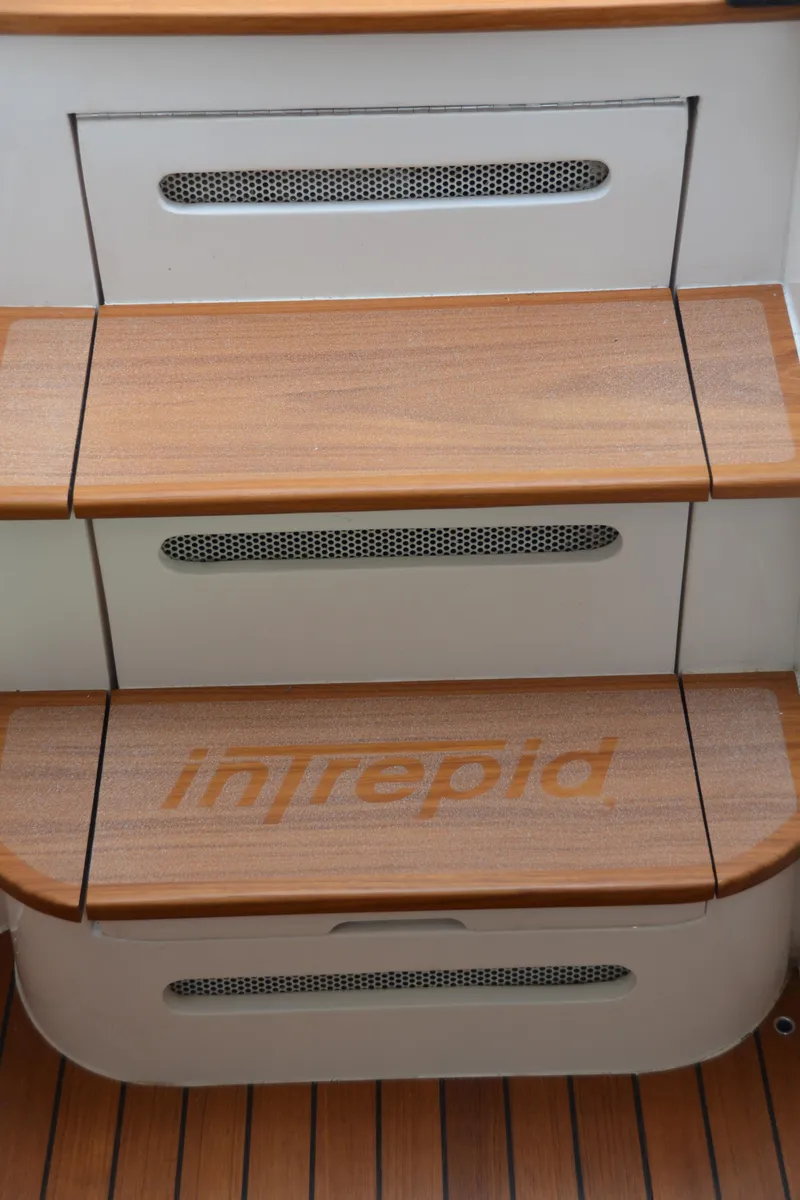 Slide: The Image of 2022 Intrepid 438 Evolution boat steps with wood finish and brand logo. - 30