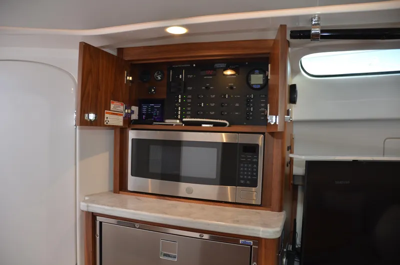 Slide: The Image of 2022 Intrepid 438 Evolution yacht interior with microwave, control panel, and cabinetry. - 34