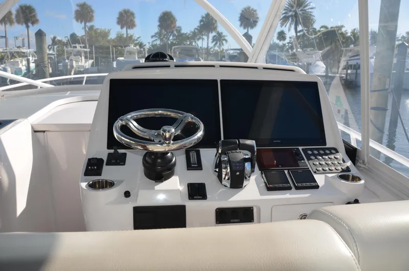 Slide: The Image of 2022 Intrepid 438 Evolution helm with dual screens and modern controls, docked near palm trees. - 4