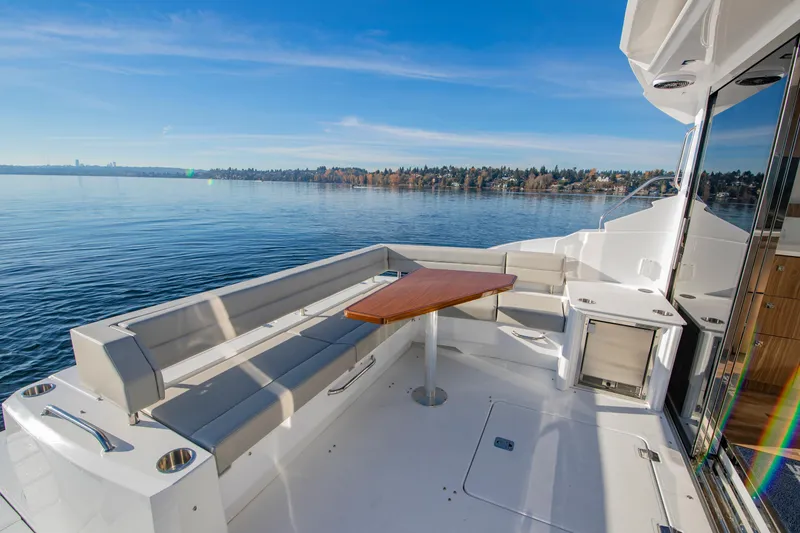 Slide: The Image of 2025 Cruisers Yachts 46 Cantius deck with seating and table, overlooking serene water. - 13