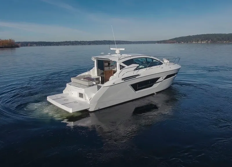 Slide: The Image of 2025 Cruisers Yachts 46 Cantius cruising on a serene lake under a clear blue sky. - 5