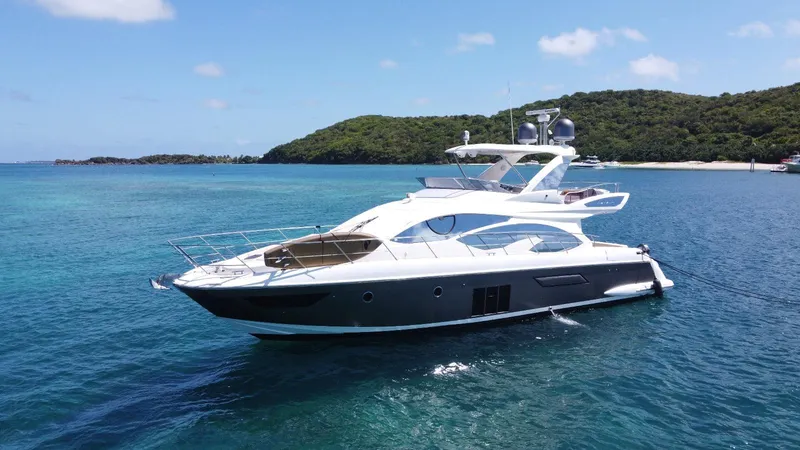 The Image of Luxurious 2016 Azimut 54fly yacht cruising in clear blue waters near a lush island. - 1