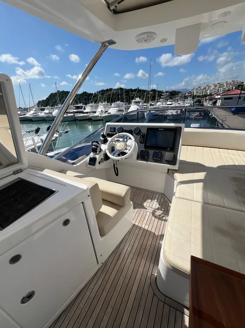 Slide: The Image of 2016 Azimut 54fly yacht helm with marina view, featuring modern controls and seating. - 14