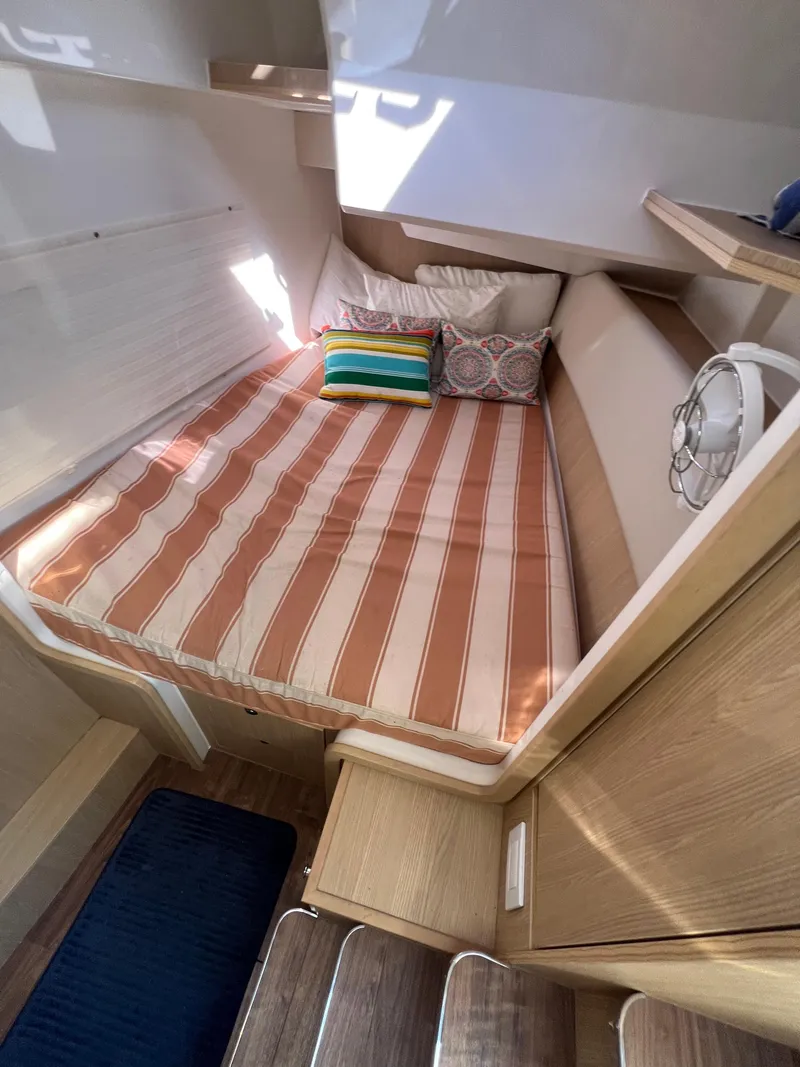 Slide: The Image of Cozy cabin interior of 2023 Aquila 36 Sport with striped bedding and colorful pillows. - 24