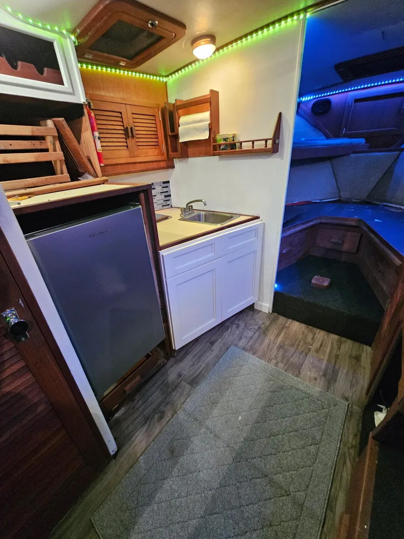 Slide: The Image of 1984 Topaz 36 Sportfisherman interior with kitchenette, sink, and cozy cabin lighting. - 13