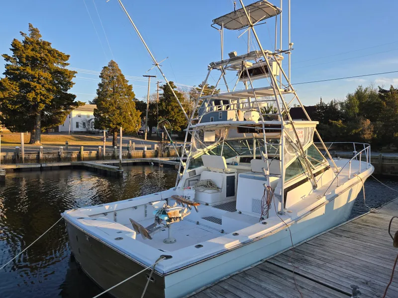 Slide: The Image of 1984 Topaz 36 Sportfisherman boat docked at a marina, surrounded by trees. - 2