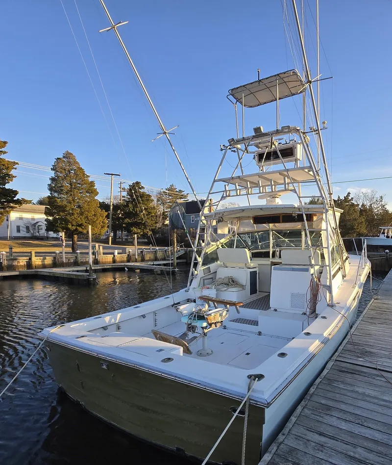 Slide: The Image of 1984 Topaz 36 Sportfisherman docked, featuring a spacious deck and tower under clear skies. - 20
