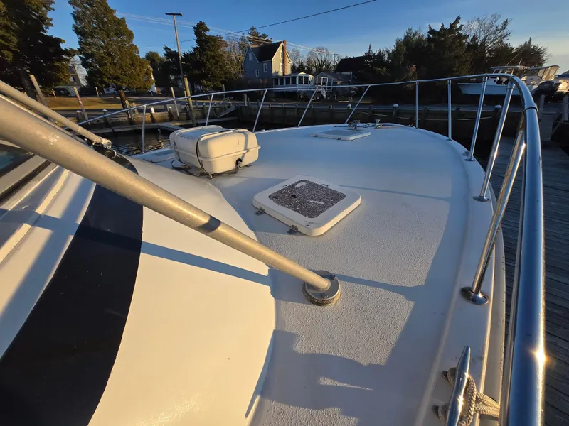 Slide: The Image of 1984 Topaz 36 Sportfisherman boat deck with railing and hatch, docked near trees. - 21