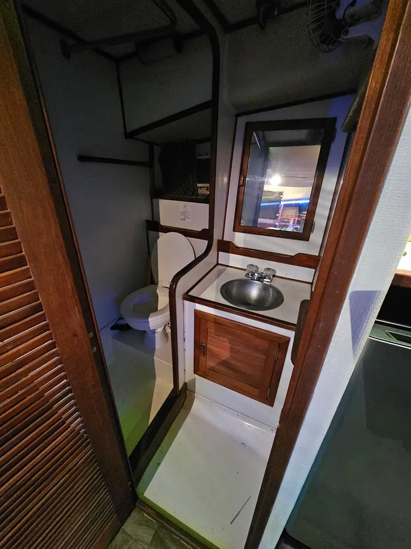 Slide: The Image of Compact bathroom in a 1984 Topaz 36 Sportfisherman boat, featuring a sink and toilet. - 8