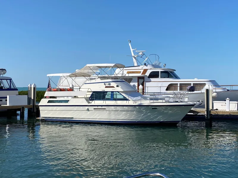 Slide: The Image of 1987 Hatteras Double Cabin yacht docked in a marina under clear blue skies. - 0