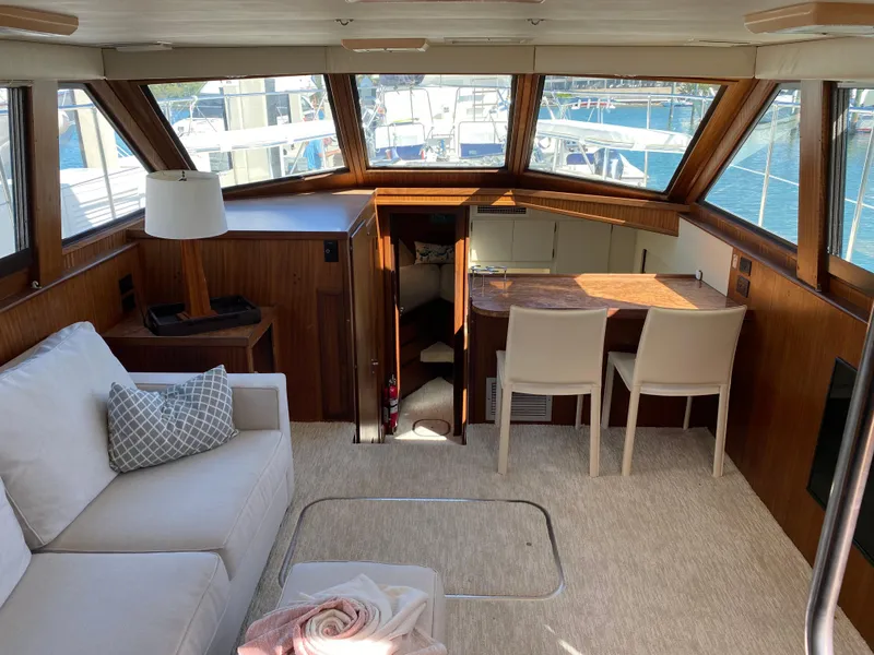 Slide: The Image of 1987 Hatteras Double Cabin interior with sofa, table, chairs, and large windows overlooking water. - 1
