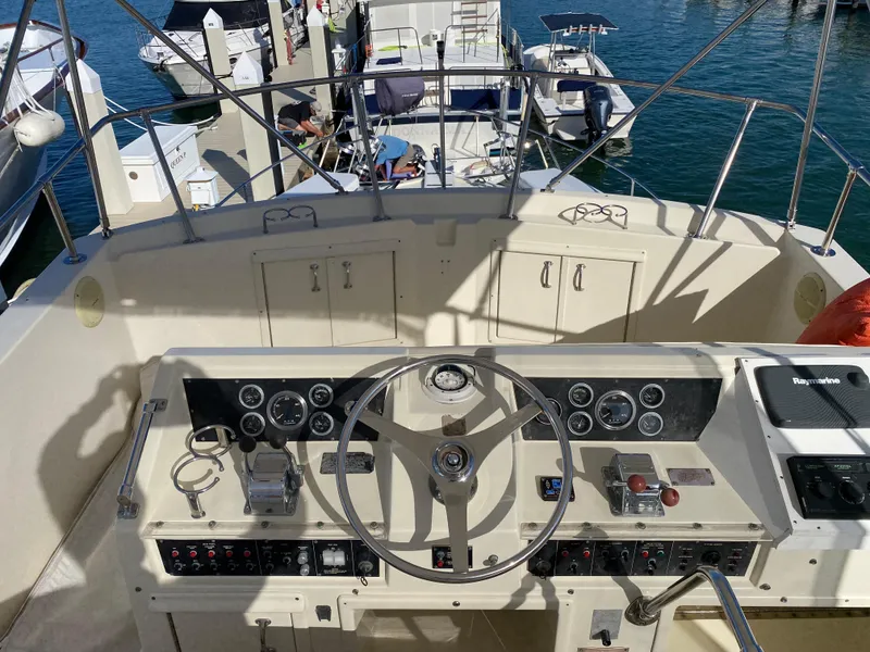 Slide: The Image of 1987 Hatteras Double Cabin helm with steering wheel and control panel, docked at marina. - 10