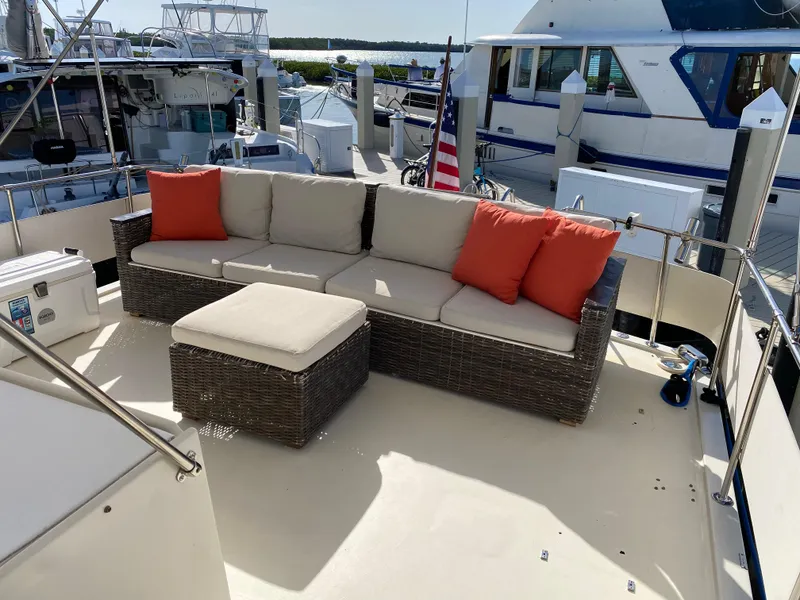 Slide: The Image of 1987 Hatteras Double Cabin yacht deck with wicker seating and orange cushions. - 12