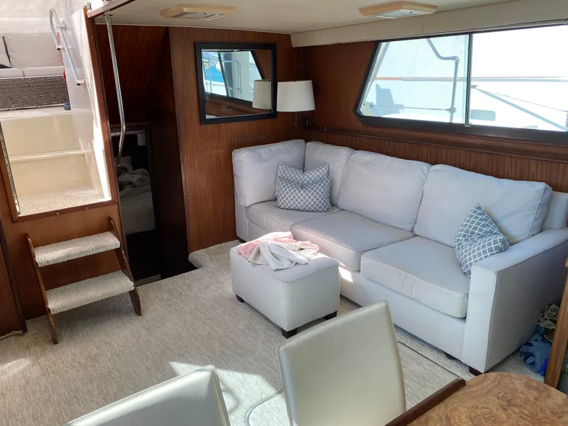 Slide: The Image of 1987 Hatteras Double Cabin interior with white sofa, wooden walls, and natural light. - 3