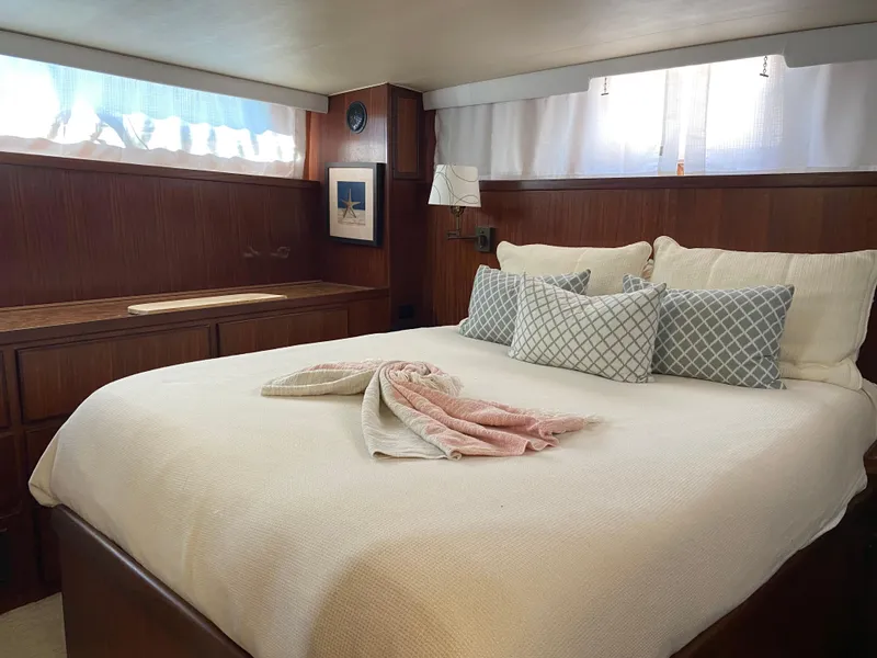 Slide: The Image of 1987 Hatteras Double Cabin bedroom with cozy bed, wooden interior, and soft lighting. - 5