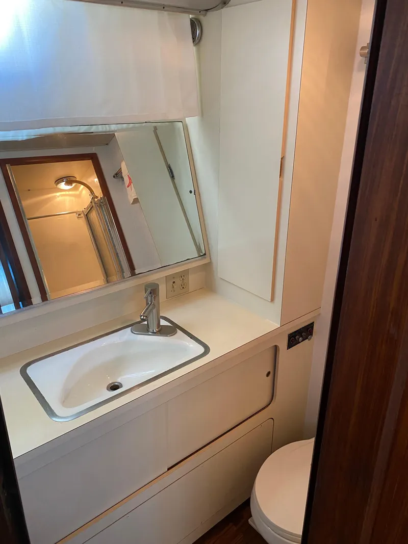 Slide: The Image of 1987 Hatteras Double Cabin bathroom with sink, mirror, and toilet. - 9