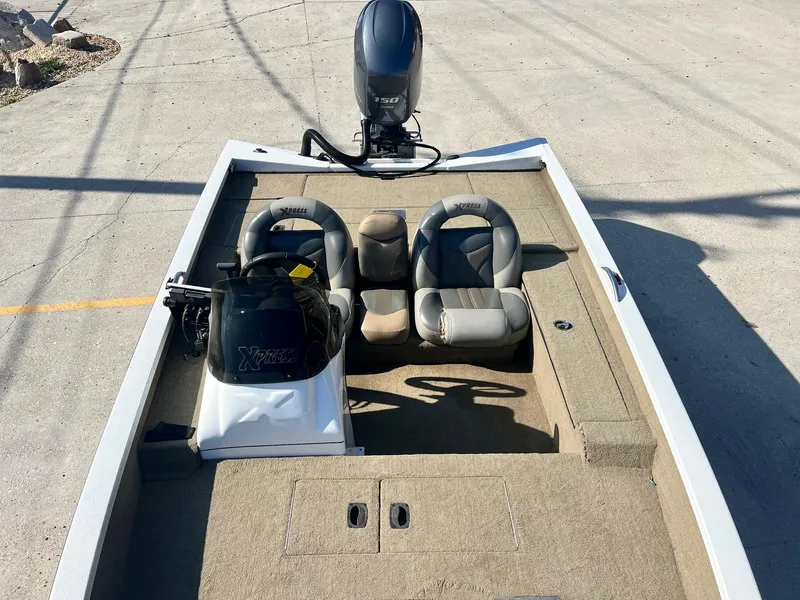 Slide: The Image of 2013 Express H18 boat with dual seats and motor, parked on concrete. - 12