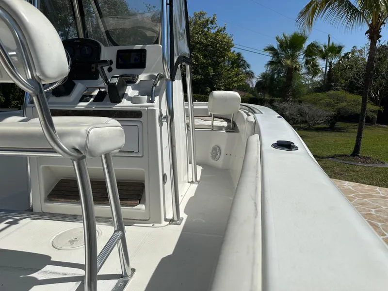 Slide: The Image of 2013 Sea Hunt Ultra 225 boat interior with seating and console, surrounded by tropical greenery. - 30