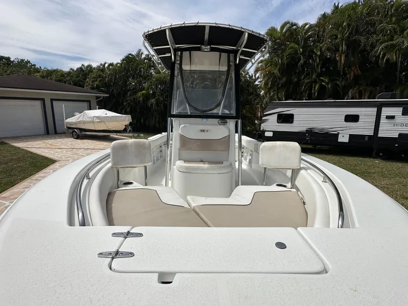 Slide: The Image of 2013 Sea Hunt Ultra 225 boat with seating, parked near a trailer and garage. - 44