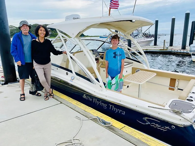 Slide: The Image of Family posing with 2021 Scout 255 Dorado boat named "The Flying Thyra" at a marina. - 15