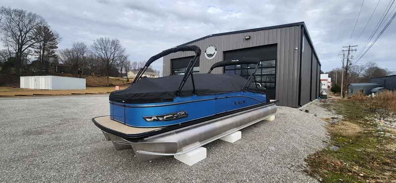 Slide: The Image of 2025 Avalon Platinum Catalina 2785 Quad Lounger Shift pontoon boat outside a metal building. - 13