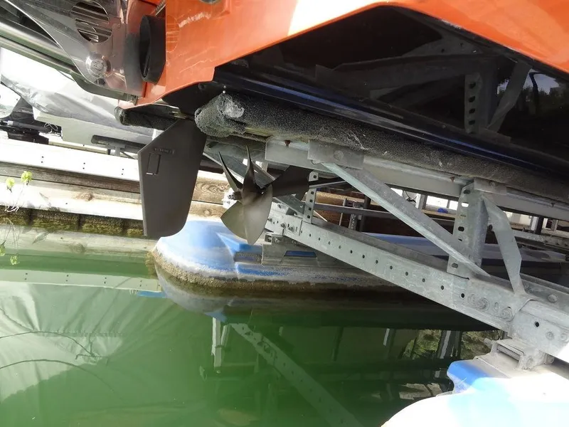 Slide: The Image of 2010 Malibu VLX WAKESETTER boat propeller and rudder on a lift over water. - 33